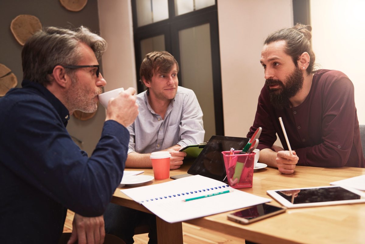 Drie collega's in overleg aan een tafel met koffie