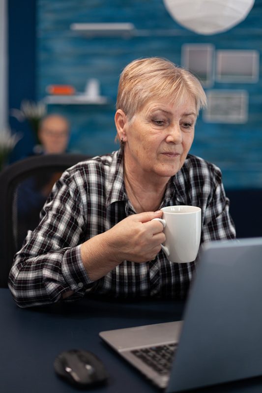 Ondernemer leest met een kop koffie mee op haar laptop